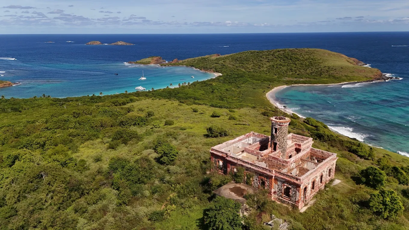 Aerial view of Culebrita lighthouse ruins overlooking green hills and turquoise Caribbean waters